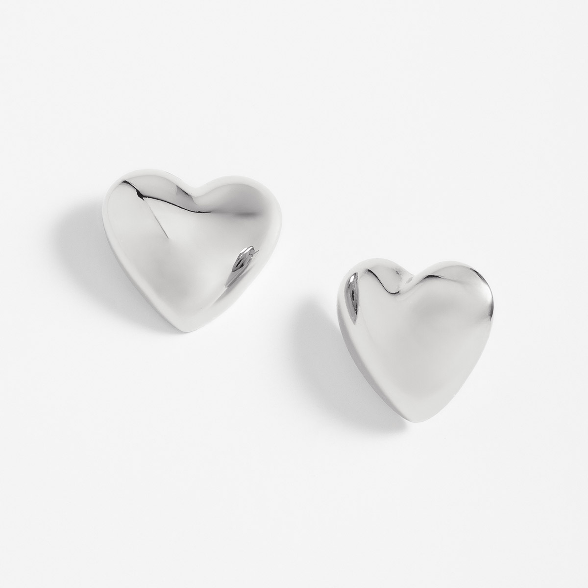 Aretes poste en baño de platino con diseño corazón pulido